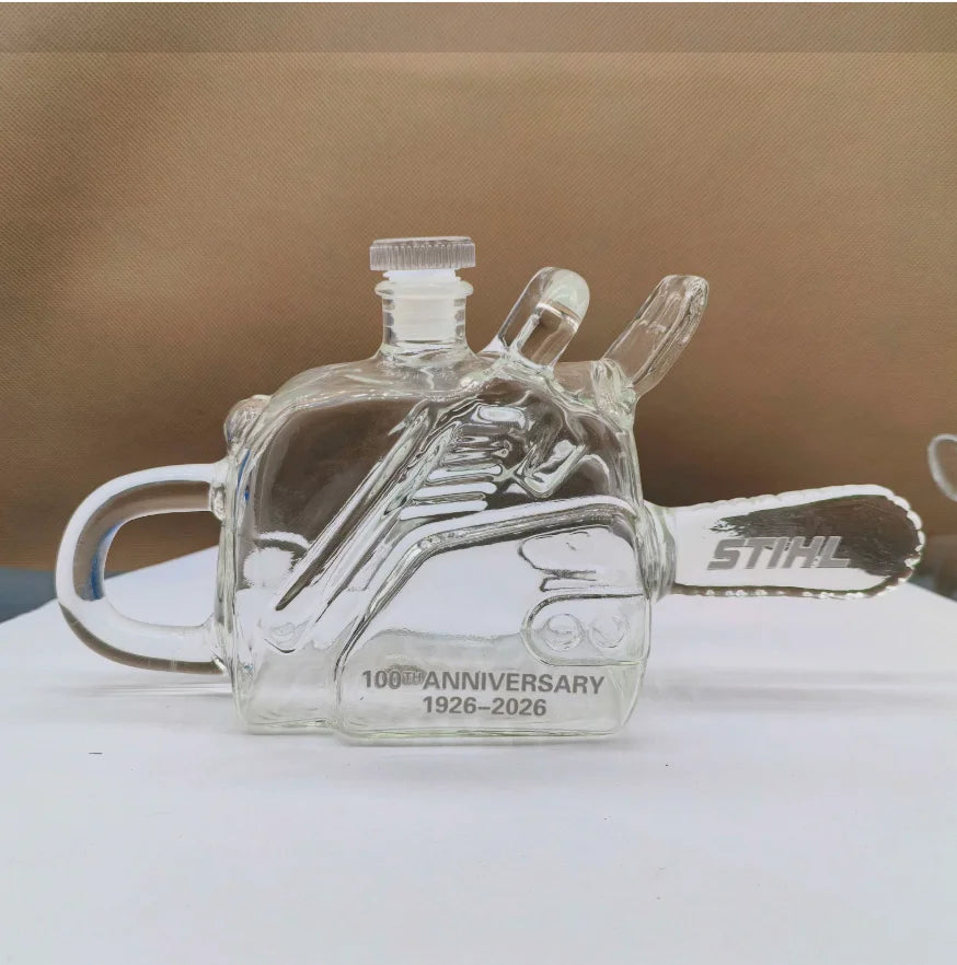 Veltora chainsaw-shaped glass whiskey decanter, 100th anniversary commemorative liquor bottle, industrial-style spirits carafe.