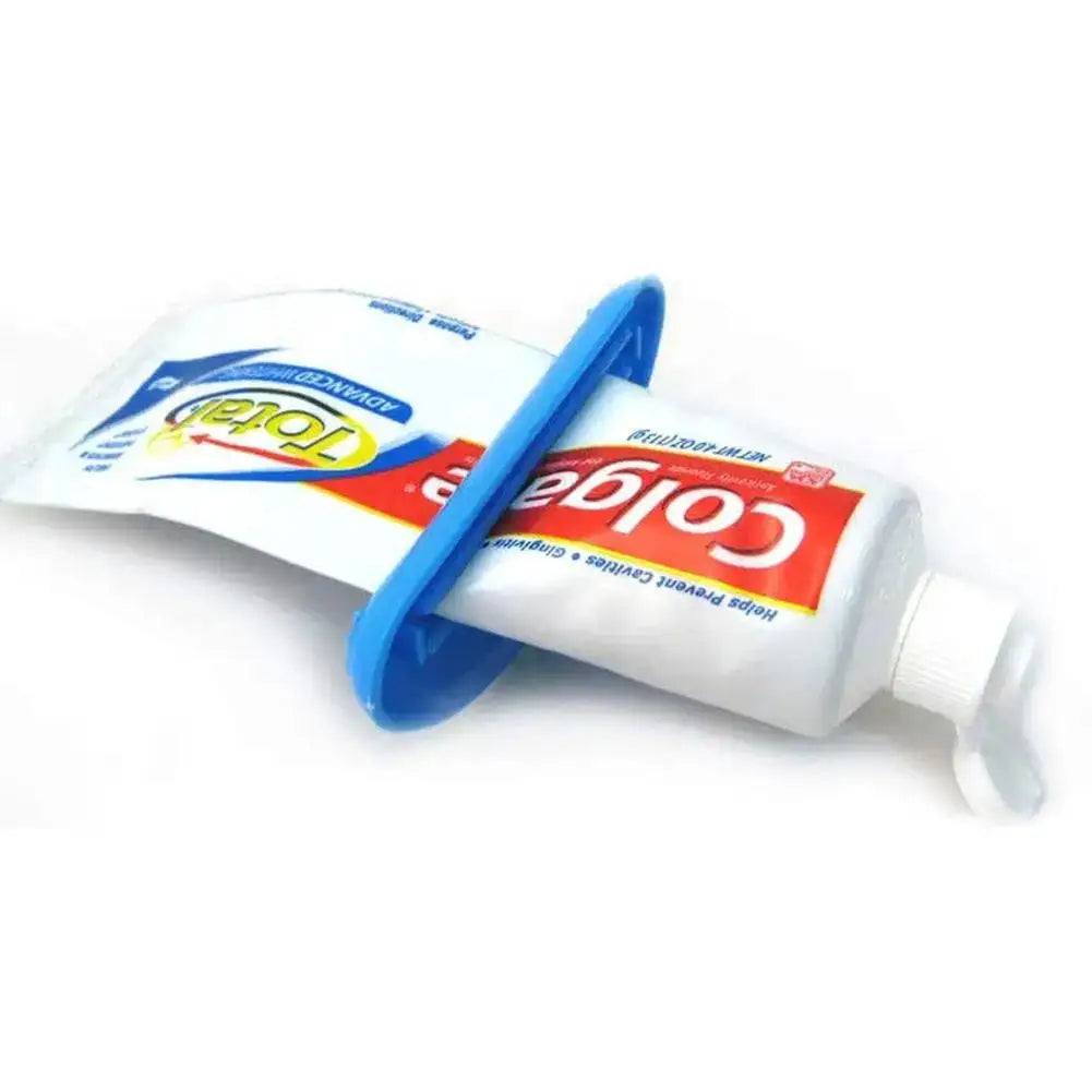 Veltora manual toothpaste dispenser and squeeze clip in use, extruding cream from a tube in a bathroom setting