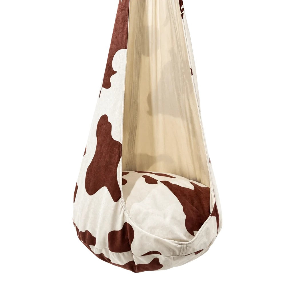 Bees&blooms Cow XXL cocoon swing for kids, soft fabric, with cow print design, hanging from a sturdy frame for outdoor play.